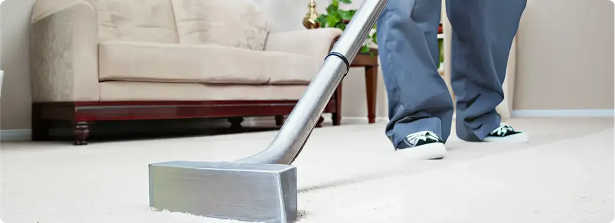 Carpet cleaning technician using a hot-water extraction wand on a light-colored carpet in a living room, Aurora, IL.