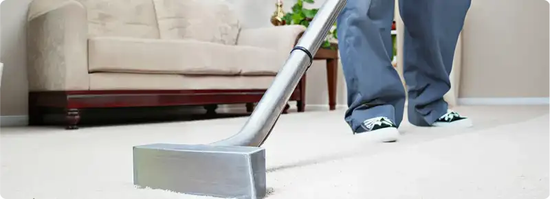 Carpet cleaning technician using a hot-water extraction wand on a light-colored carpet in a living room, Aurora, IL.