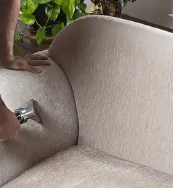 Professional upholstery cleaner deep-cleaning a fabric sofa with a handheld extraction tool and hose Aurora, IL.
